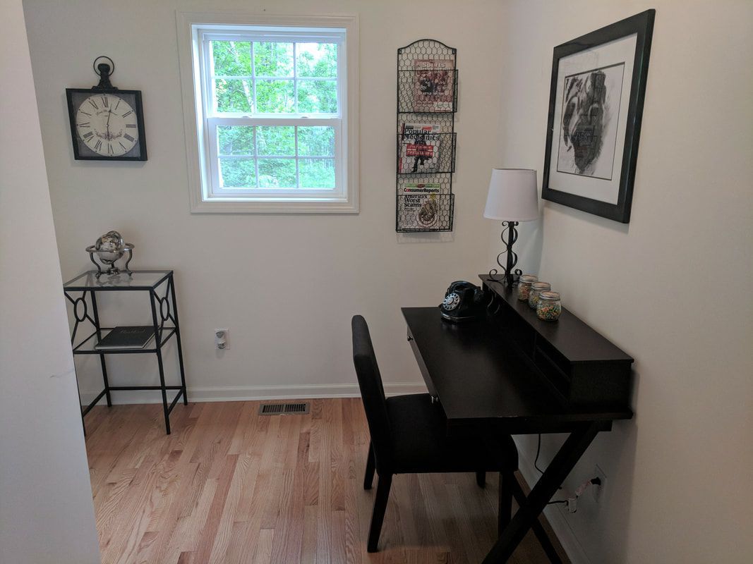 There is a clock on the wall above the desk in the room.