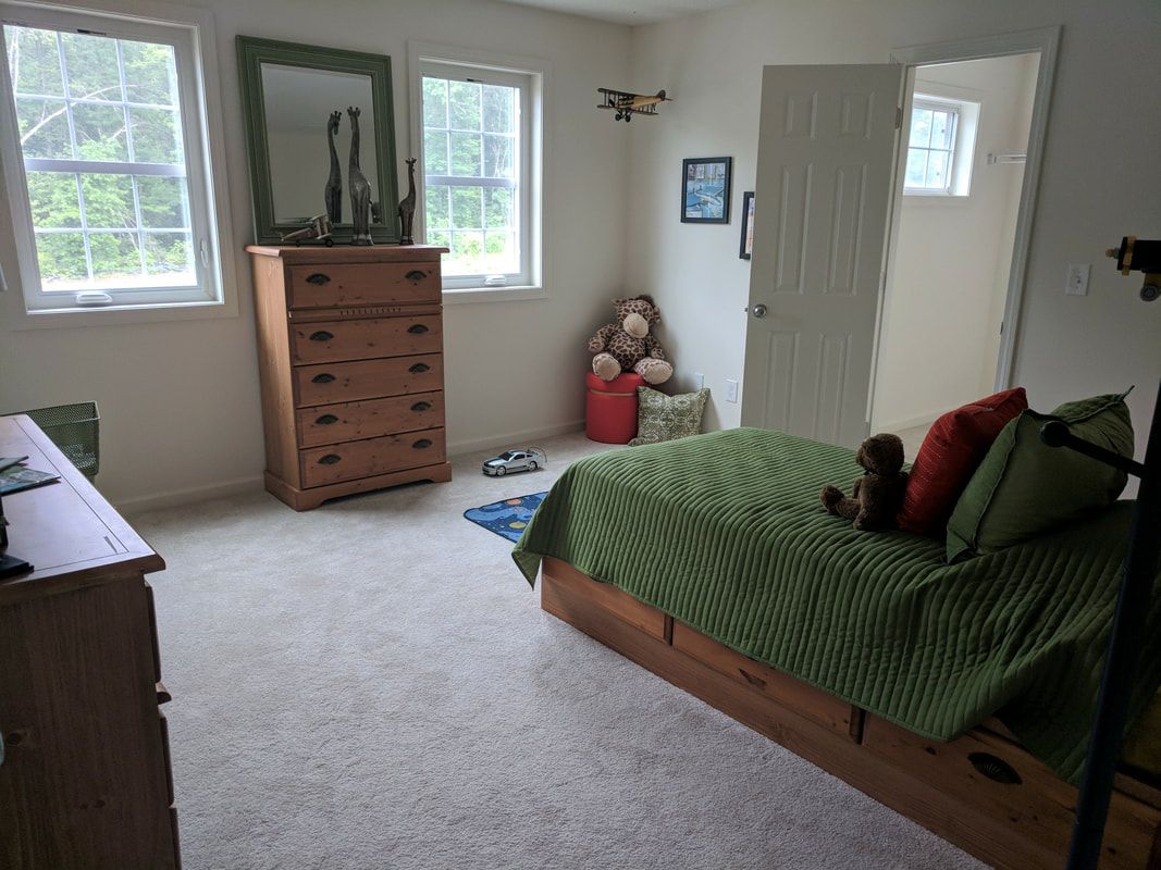 A bedroom with a bed , dresser , mirror and window.