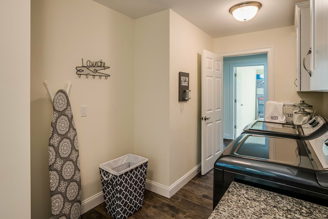 A laundry room with a washer and dryer and an ironing board.
