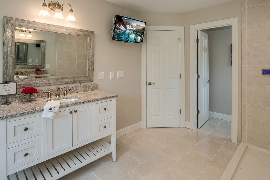 A bathroom with two sinks , a mirror and a television.