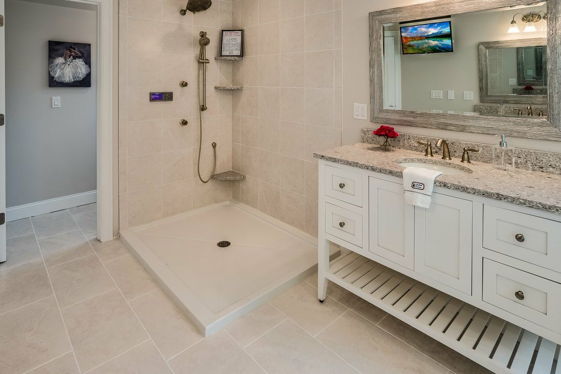 A bathroom with a walk in shower , sink and mirror.