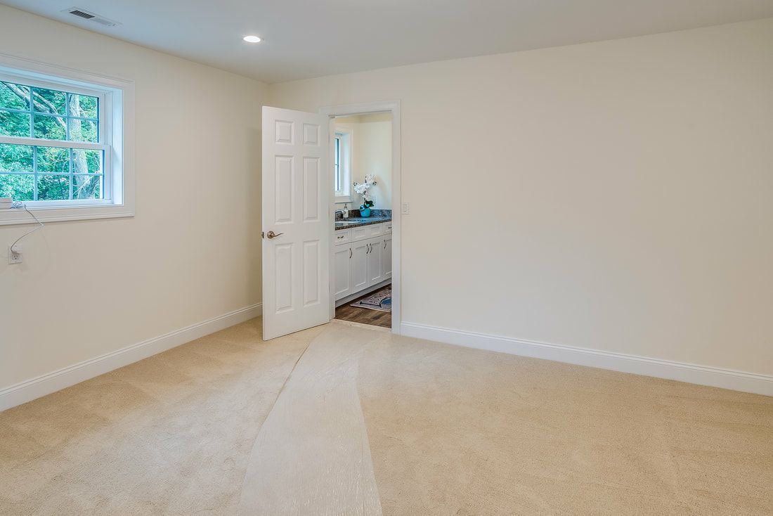 An empty room with a window and a door leading to a bathroom.