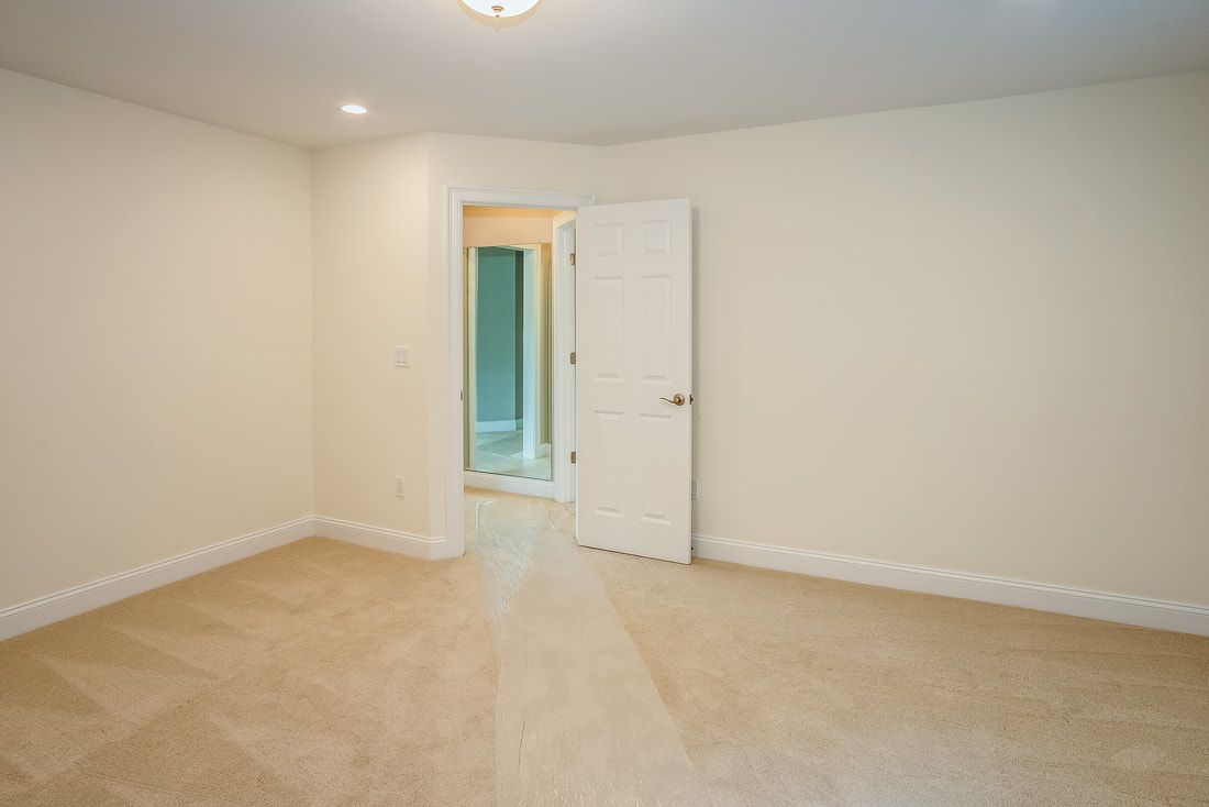 An empty bedroom with a carpeted floor and white walls.