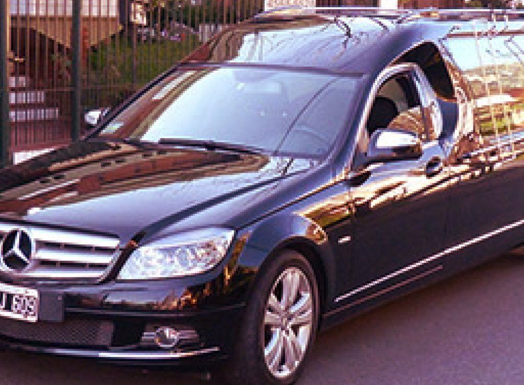 Coche fúnebre negro con detalles plateados estacionado en la calle.