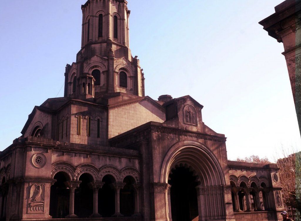 Mausoleo de piedra con entrada arqueada y torre alta contra un cielo azul.
