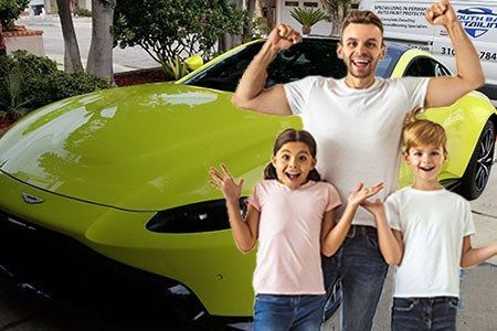A man and two children are standing in front of a yellow sports car.
