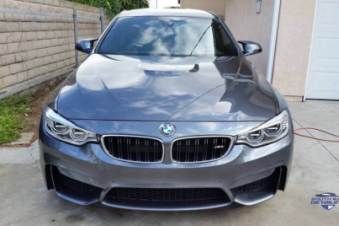 A bmw m3 is parked in a driveway next to a garage.