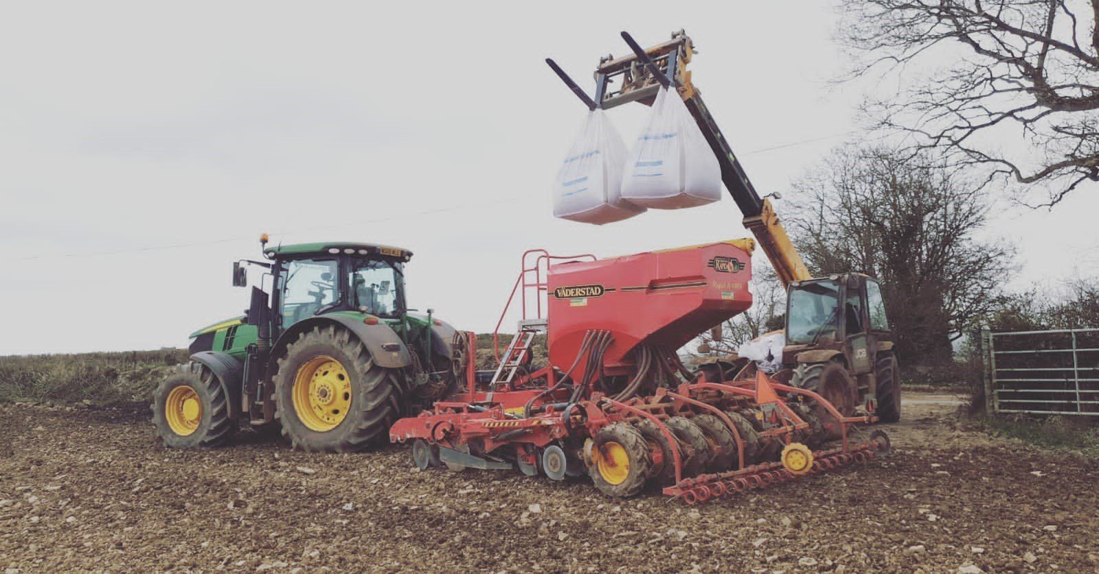 a john deere tractor is being pulled by a valtra planter