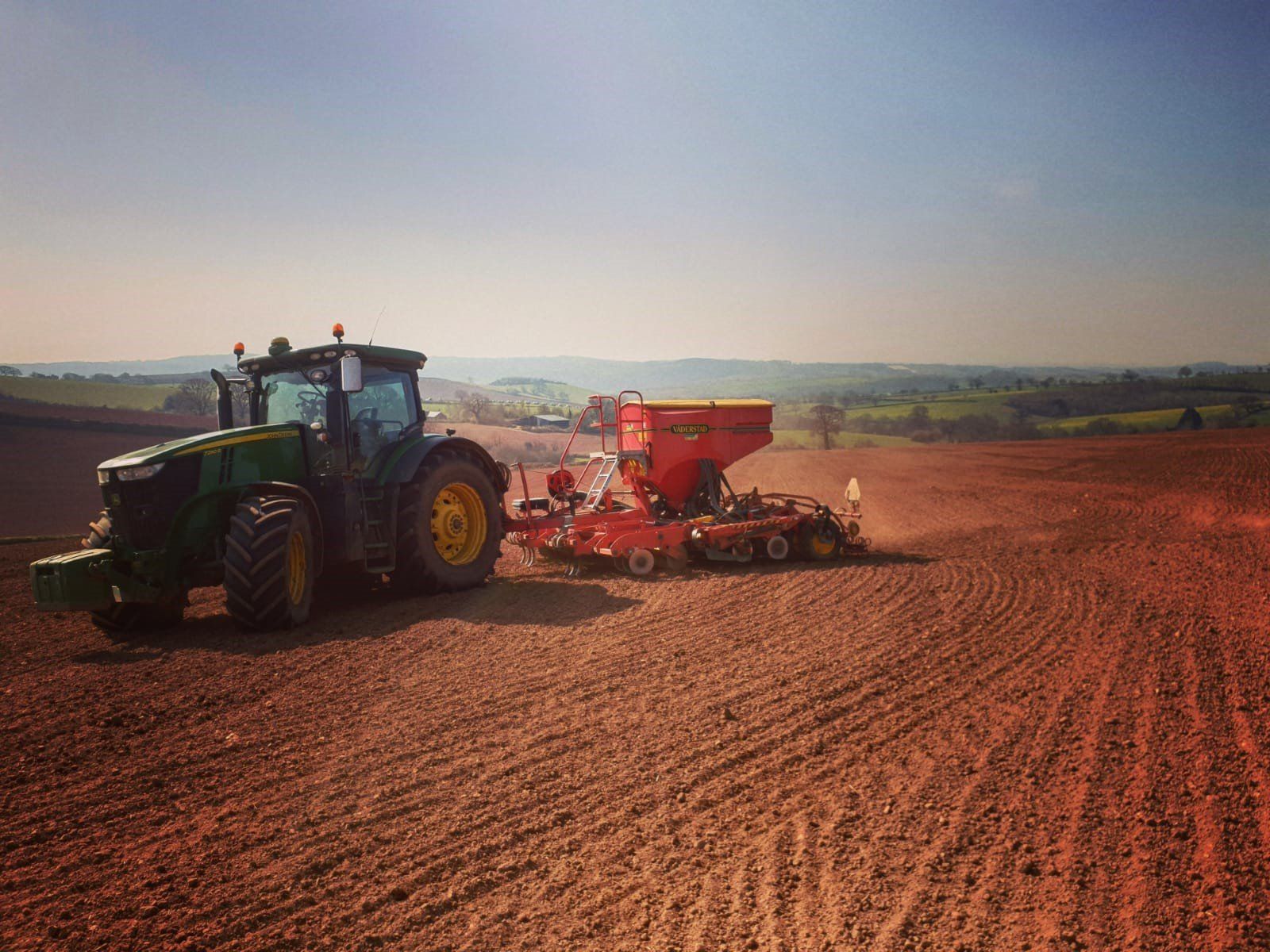 a john deere tractor is plowing a field