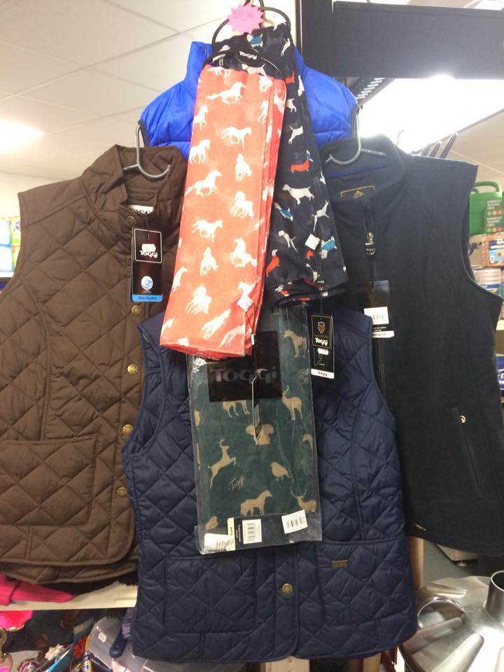 a quilted vest and a scarf with horses on them are hanging on a rack