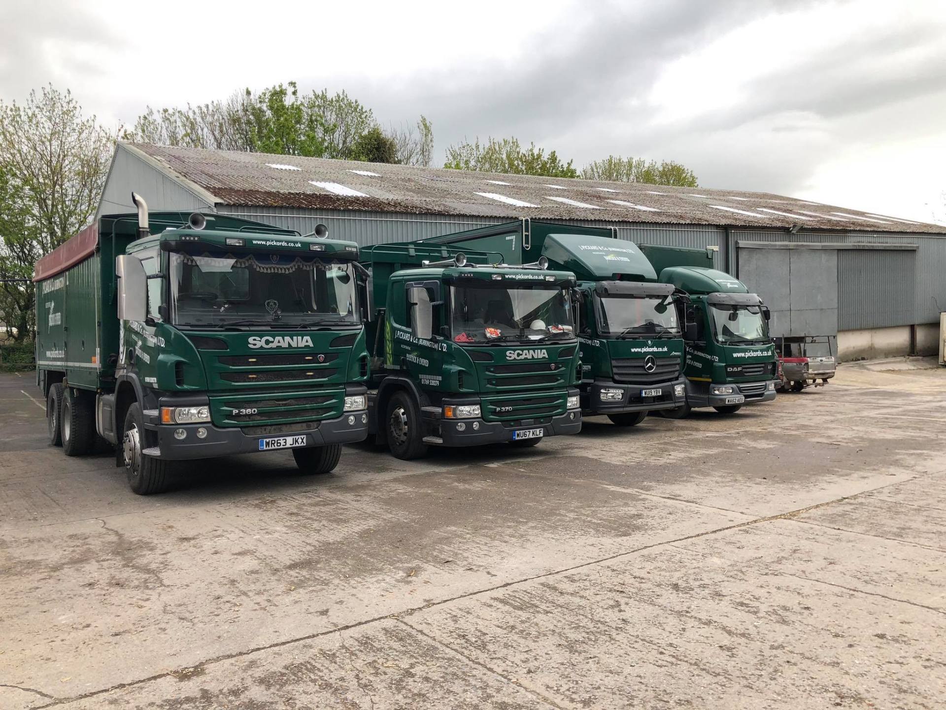 a row of green scania trucks parked in front of a building