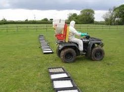 a man in a protective suit is riding an atv in a field .