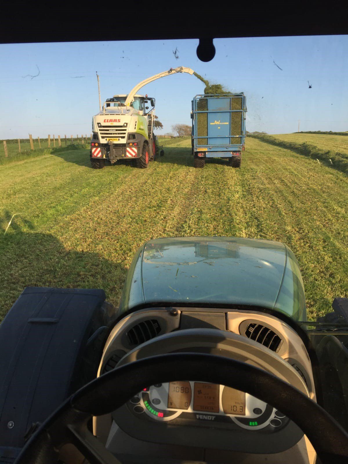 a claas tractor is cutting grass in a field