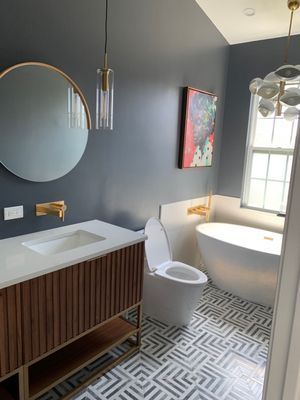 A bathroom with a toilet , sink , tub and mirror.