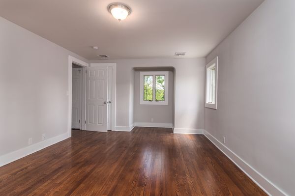 An empty room with hardwood floors and white walls.
