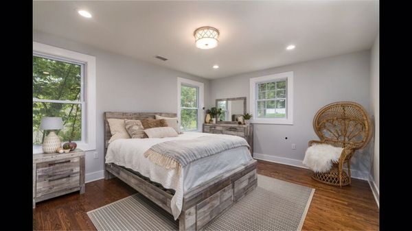A bedroom with a bed , dresser , nightstand and chair.