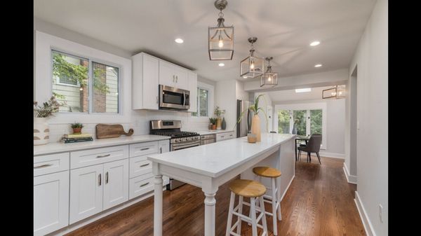 A kitchen with white cabinets and hardwood floors and a large island.