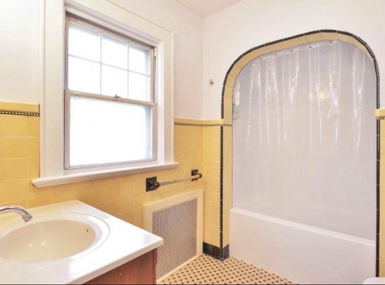 A bathroom with yellow tiles and a white tub