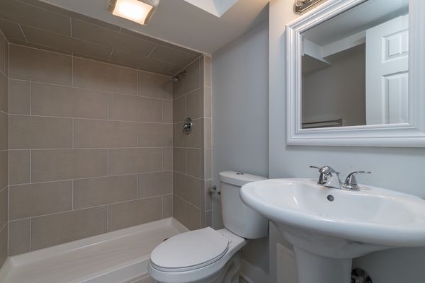 A bathroom with a toilet , sink , and mirror.