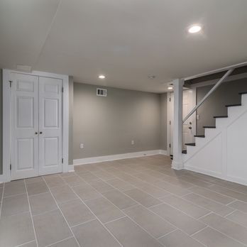An empty basement with tile floors and stairs.