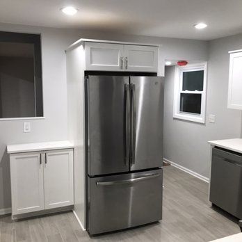 A kitchen with a stainless steel refrigerator and white cabinets.