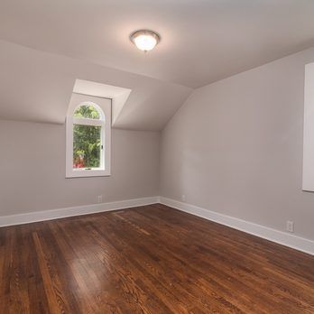 An empty room with hardwood floors and a window.