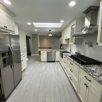 A kitchen with white cabinets , stainless steel appliances and granite counter tops.