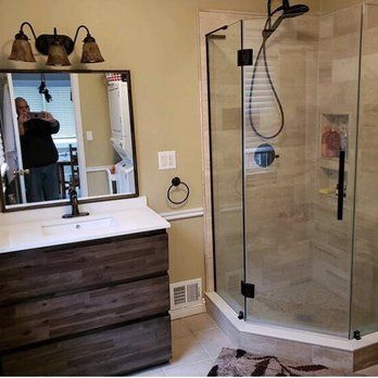 A bathroom with a sink , mirror , and shower stall.