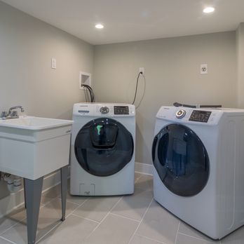 A laundry room with two washing machines and a sink.