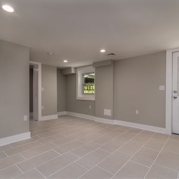 An empty basement with tile floors and a window.