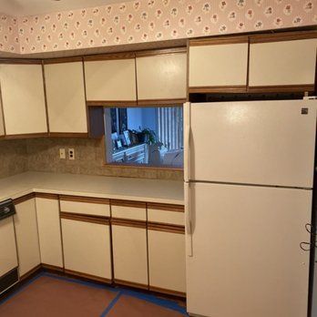 A kitchen with white cabinets and a white refrigerator.