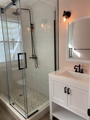 A bathroom with a walk in shower , sink and mirror.