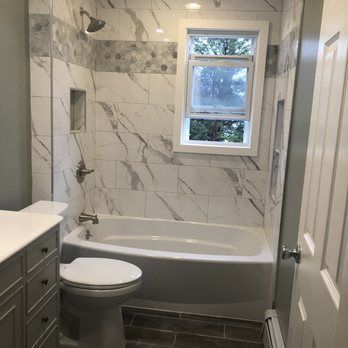 A bathroom with a tub , toilet , sink and window.