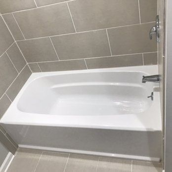 A white bathtub is sitting in a bathroom next to a tiled wall.