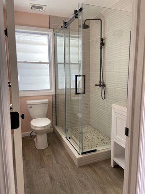 A bathroom with a toilet , sink , shower and window.