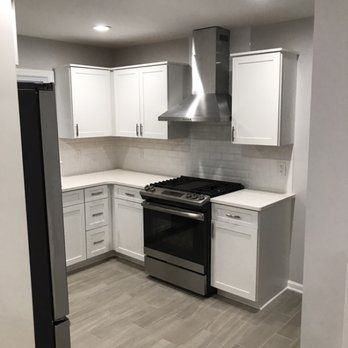 A kitchen with white cabinets , a stove , and a refrigerator.
