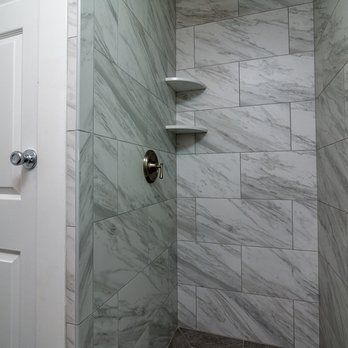 A bathroom with marble tiles and a walk in shower.