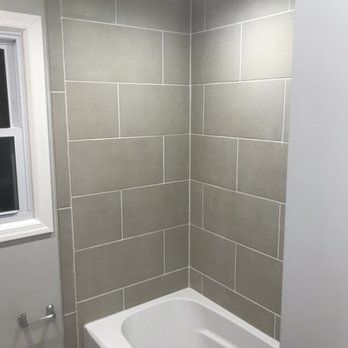 There is a bathtub in the corner of the bathroom next to a window.