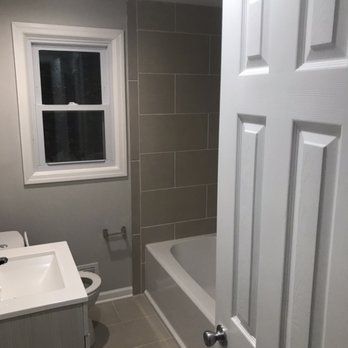 A bathroom with a sink , toilet , tub and window.
