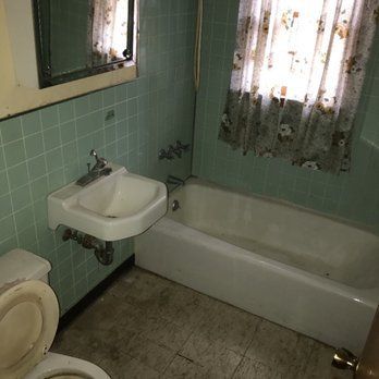 A bathroom with a toilet , sink , tub and mirror.