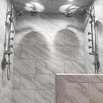 There are two shower heads in the shower with marble tiles.