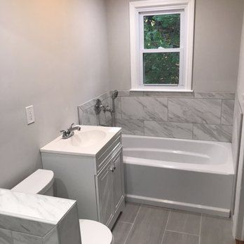 A bathroom with a sink , toilet , tub and window.