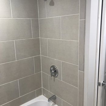 A bathroom with a bathtub , shower , and tiled walls.