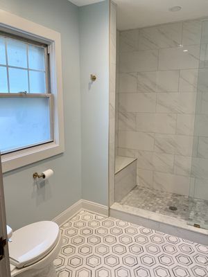 A bathroom with a toilet , shower and window.