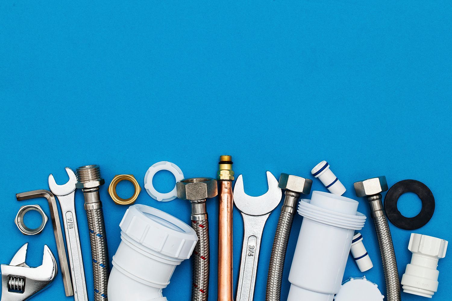 View of various plumbing tools and materials, like wrenches and pip-es against a blue background.
