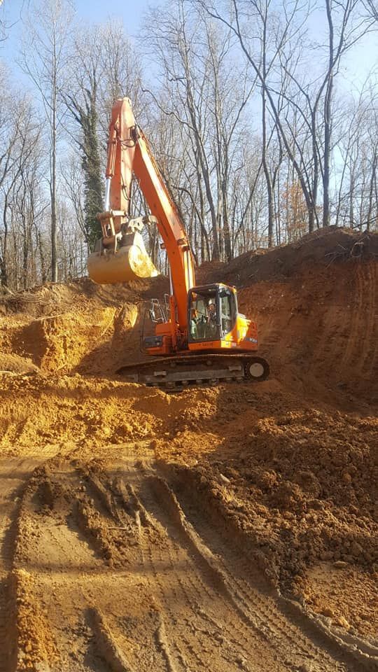 Orange excavator digging into a dirt hillside.