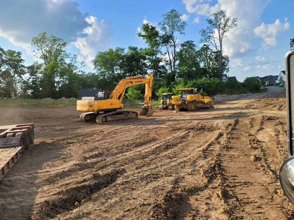 Excavator and bulldozer on a dirt construction site, clearing land on a sunny day.
