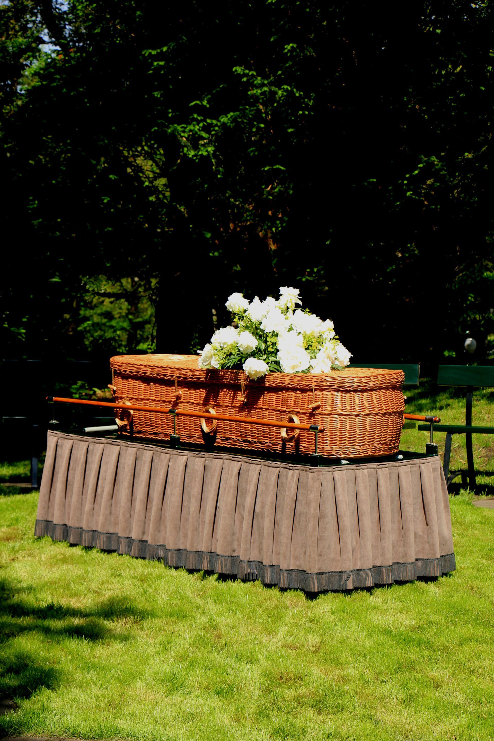 A man in a suit is sitting at a coffin at a funeral.