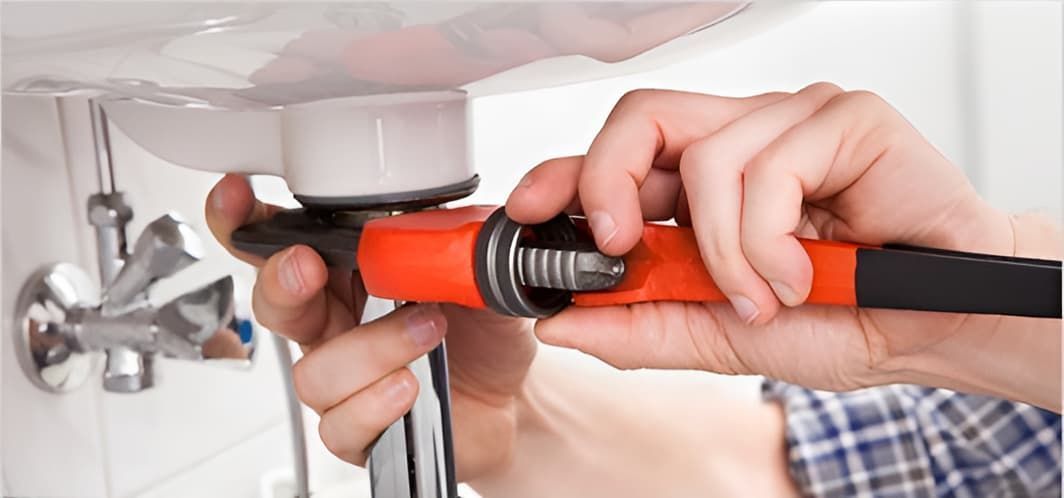 A Person is Fixing a Sink With a Wrench — John Day Plumbing in Casuarina, NT