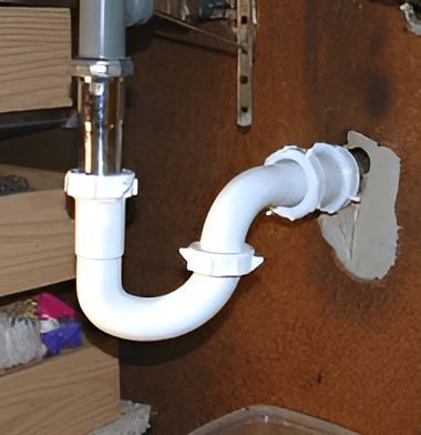 A White Pipe is Attached to a Brown Wall — John Day Plumbing in Casuarina, NT